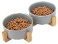 Zwei graue Haustierfutternäpfe mit Holzständern, gefüllt mit Trockenfutter.