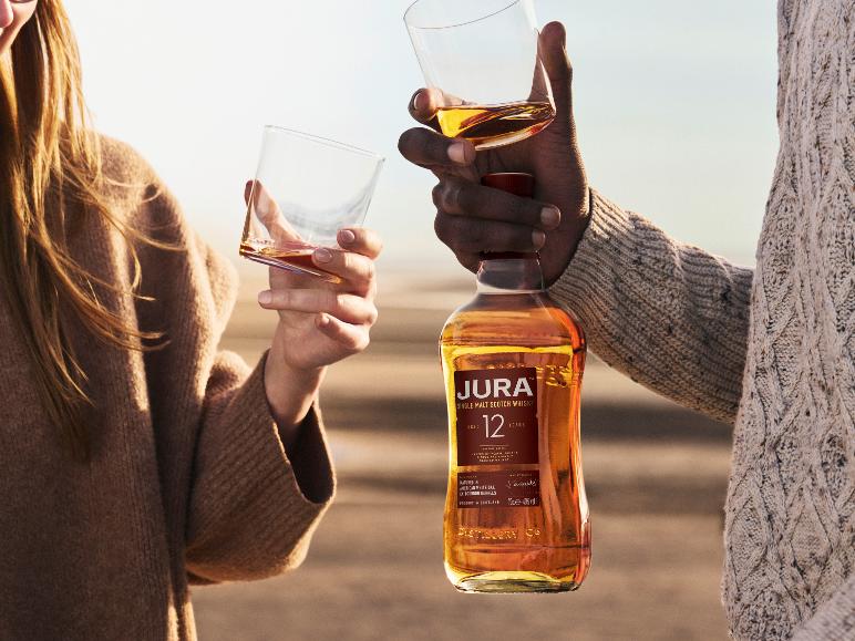 Zwei Personen halten eine Flasche Jura 12 Jahre alten Single Malt Scotch Whisky und Gläser.