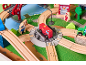Holzeisenbahn-Set mit rotem Feuerwehrauto, Schienen und Figuren auf einer Spielmatte.