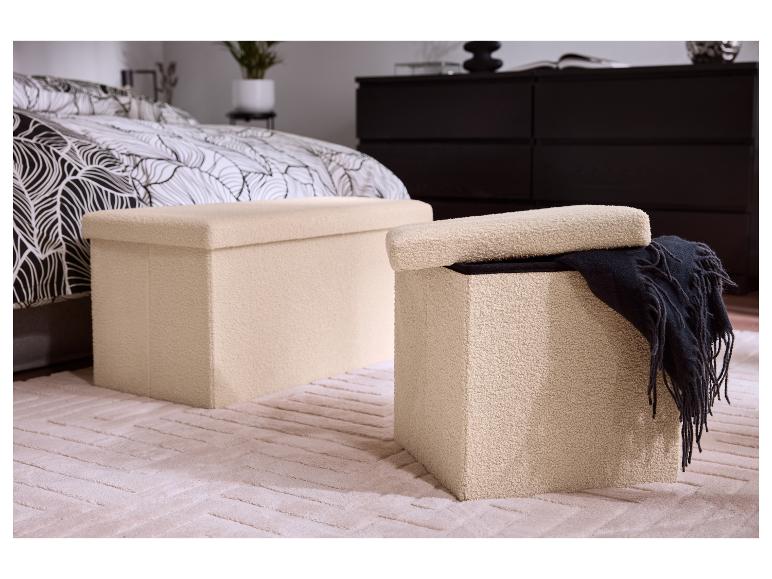 Zwei beige Aufbewahrungshocker in einem Schlafzimmer mit gemusterter Bettdecke und dunkler Kommode.