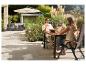 Paar entspannt auf der Terrasse mit Gartenmöbeln und Sonnenschirm.