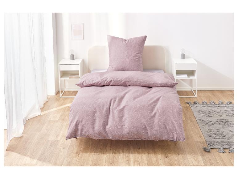 Rosa Bettwäsche auf einem Bett in einem hellen Schlafzimmer.