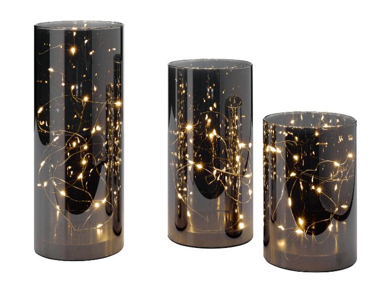 Drei zylindrische Glaslaternen mit warmen Lichterketten im Inneren, unterschiedlich hoch.