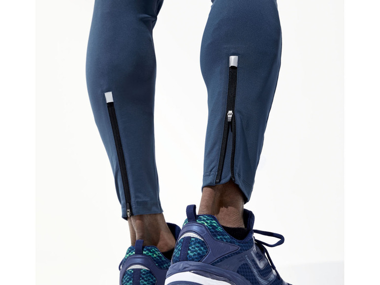 Mann trägt blaue Sporthose mit Reißverschlüssen an den Seiten und blaue Sportschuhe.