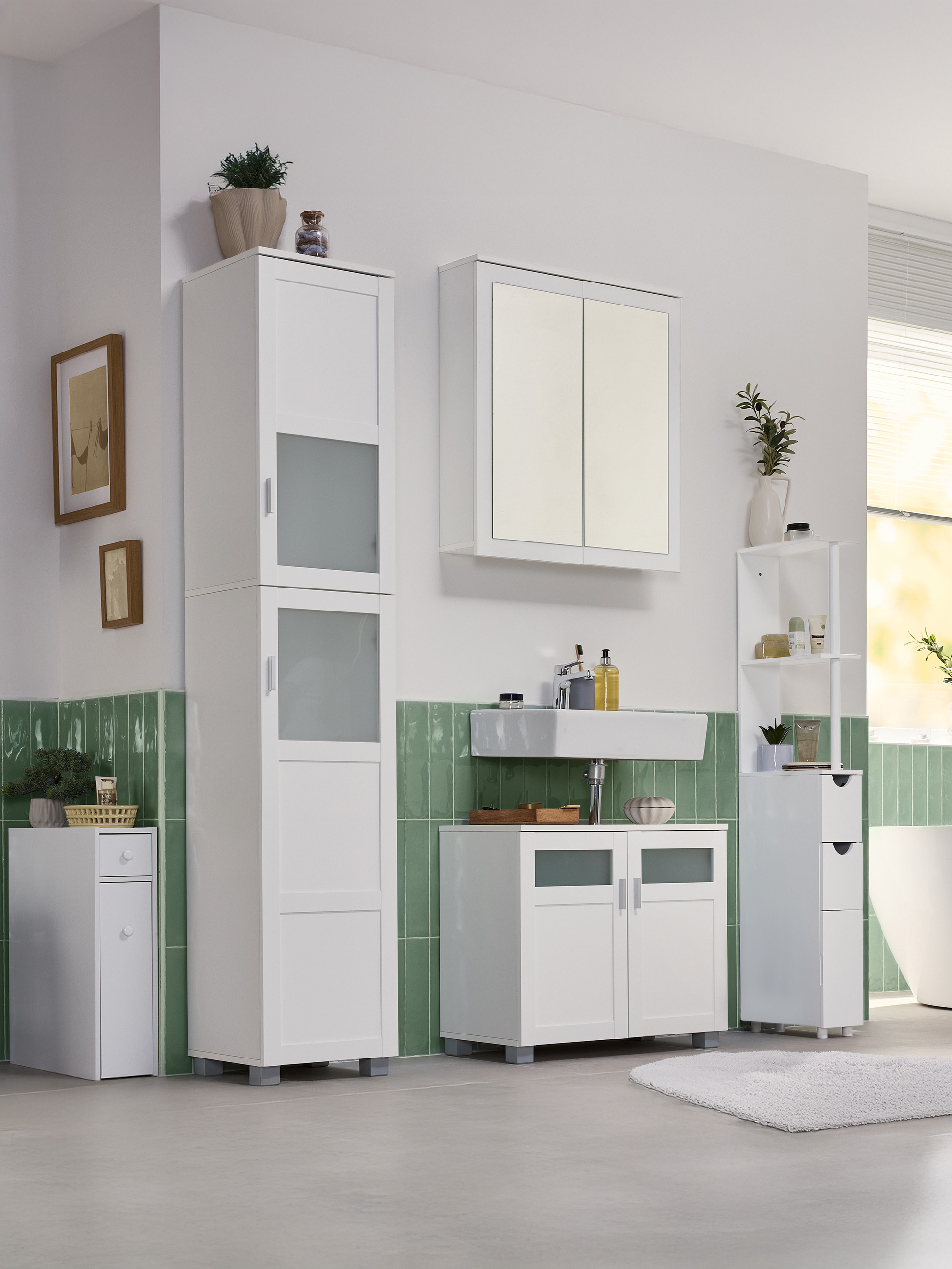 Badezimmer mit weißen Schränken, Waschbecken und grünen Wandfliesen.