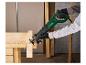 Mann in Handschuhen sägt ein Holzbrett mit einer elektrischen Säbelsäge an einer Werkbank.