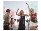 Festivalbesucher tanzen in Boho-Style mit Taschen.