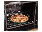 Frisch zubereitete Pizza in einer grünen Backform, auf einem Rost in einem offenen Ofen.