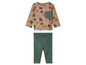 Ein beiges Baby-T-Shirt mit Cowboyhut-Muster und grüne Leggings.