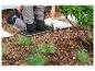 Person kniet auf einem Gartenkissen und benutzt eine Handschaufel für die Gartenarbeit.