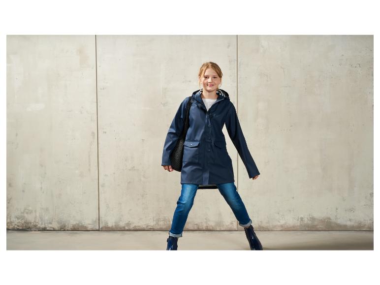 Ein Mädchen in einem blauen Regenmantel, Jeans und Stiefeln.