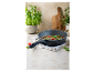 Bratpfanne mit einem gekochten Gericht, garniert mit Basilikum und Kirschtomaten.