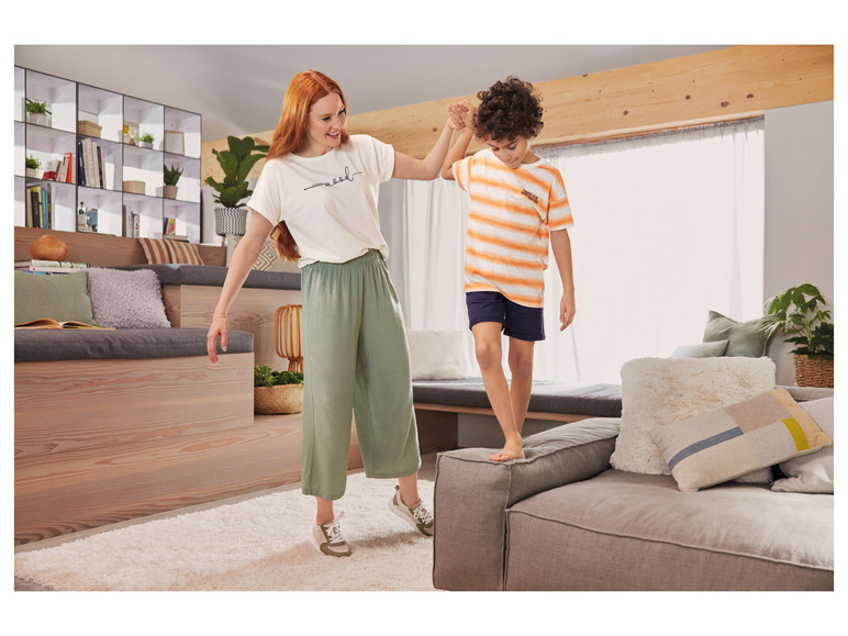 Eine Frau und ein Junge in legerer Kleidung spielen auf einem Sofa.