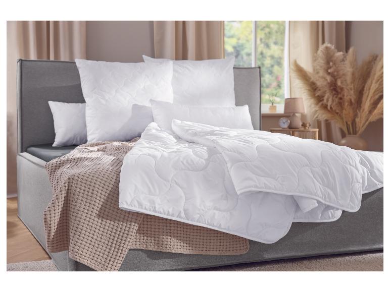Schlafzimmer mit grauem Bett, weißen Bettdecken und Kissen, beiger Decke.