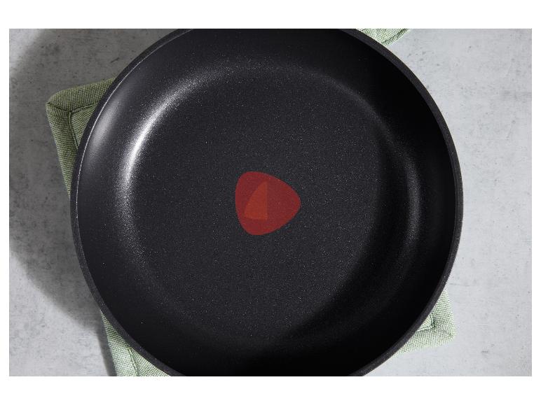 Draufsicht auf eine schwarze Antihaftpfanne mit rotem Thermo-Spot auf einem grünen Tuch