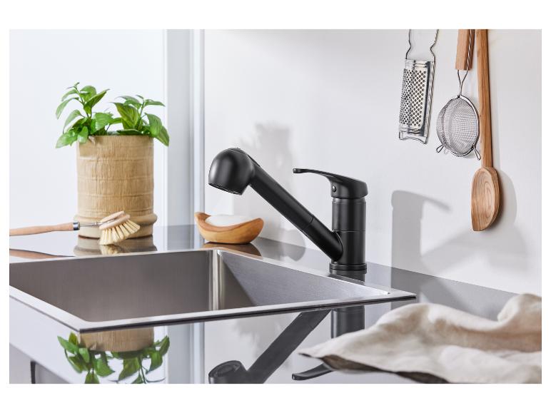 Schwarze Küchenarmatur, Edelstahlspüle, Küchenutensilien.