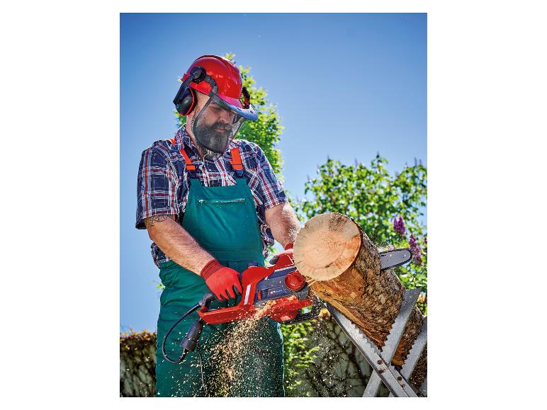 Mann in Schutzkleidung sägt Holz mit einer Kettensäge.