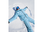 Eine Frau im hellblauen Skianzug macht einen Schneeengel.