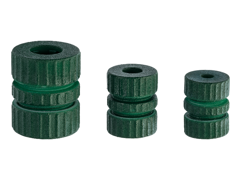 Drei Stapel grüner, zylindrischer Kunststoffteile in unterschiedlichen Höhen.