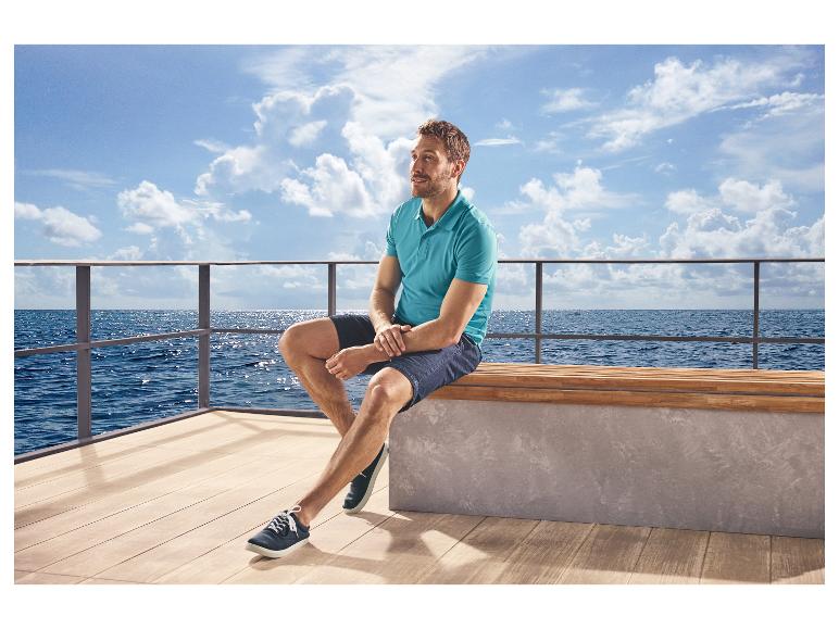 Mann in blauem Poloshirt und Shorts, trägt ESMARA MEN Freizeitschuh, sitzt am Meer.
