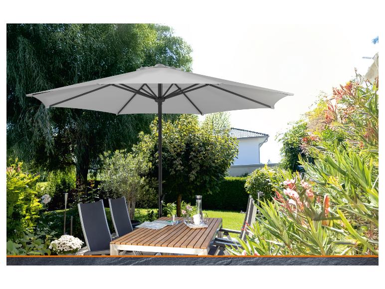 Grauer Sonnenschirm und Holztisch mit Stühlen in einem grünen Garten.