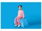 Mädchen in rosa Pullover und Hose sitzt auf einem blauen Pouf.