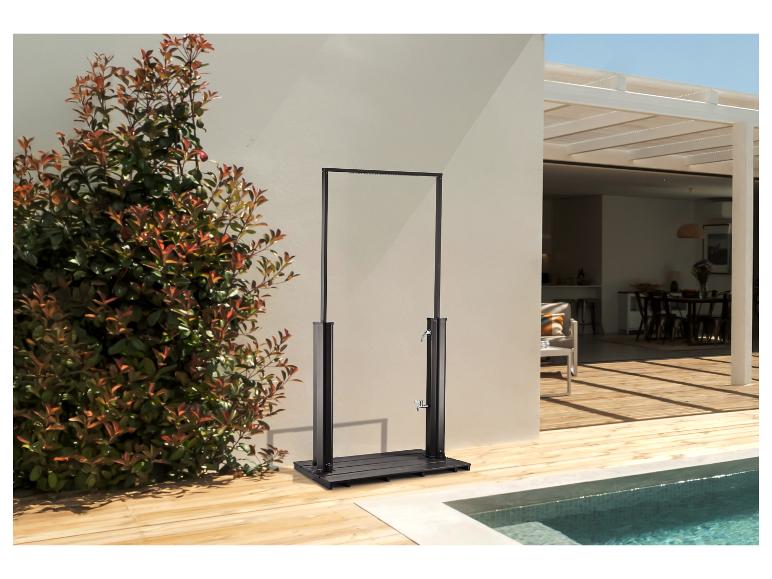 Außendusche mit schwarzem Rahmen und Holzsockel neben einem Pool und grünen Pflanzen.