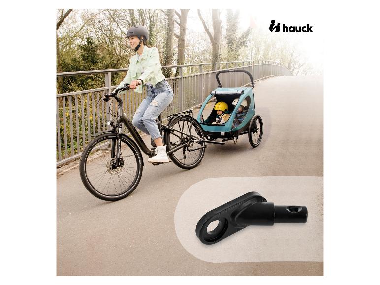 Frau auf Fahrrad zieht Hauck Kinderanhänger mit zwei Kindern.