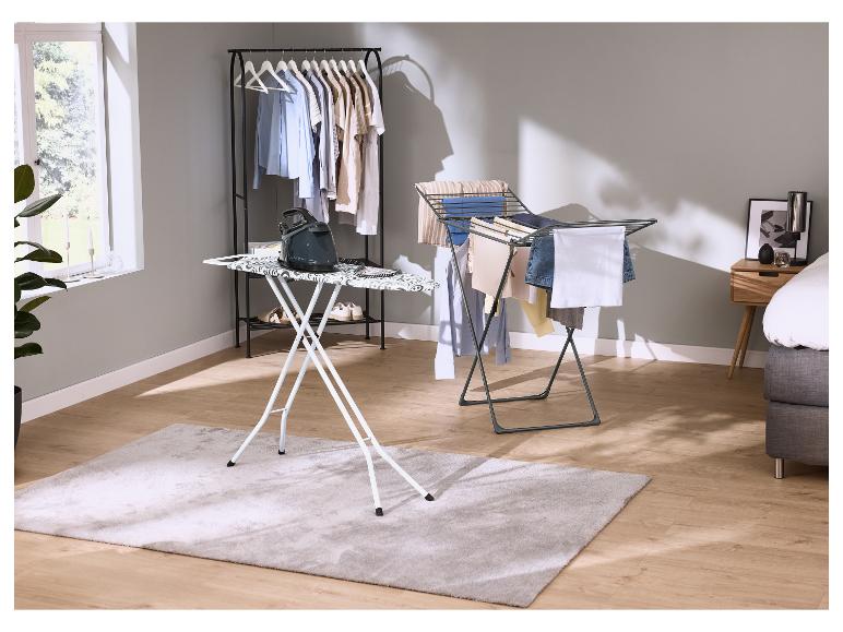 Bügelbrett mit Bügeleisen, Kleiderständer und Wäscheständer im Schlafzimmer.