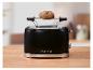 Schwarzer Toaster mit Brötchen auf dem Rost, auf einer Holzplatte, mit „1973“.