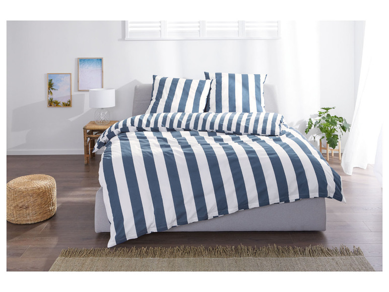 Ein gestreiftes Bettbezug in Blau und Weiß auf einem Bett.
