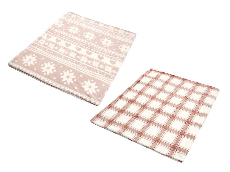 Zwei weiche Decken, eine mit Schneeflocken- und Herzmustern, die andere kariert.