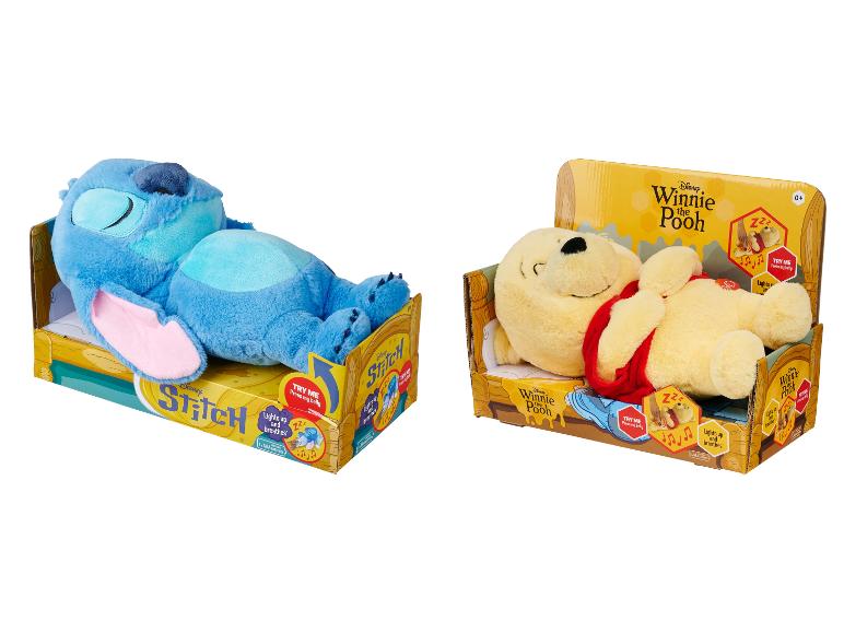 Zwei Plüschtiere, ein blauer Außerirdischer und ein gelber Bär, in Kartons, beide mit dem Text „Leuchtet und atmet“.