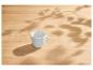 Weiße Tasse auf einem hellen Holztisch mit Blattschatten