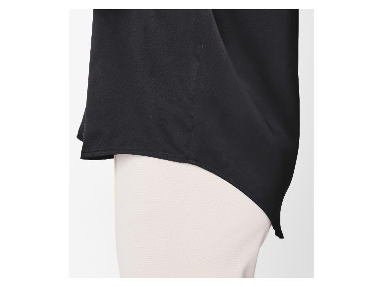 Schwarze Bluse mit asymmetrischem Saum über heller Hose.