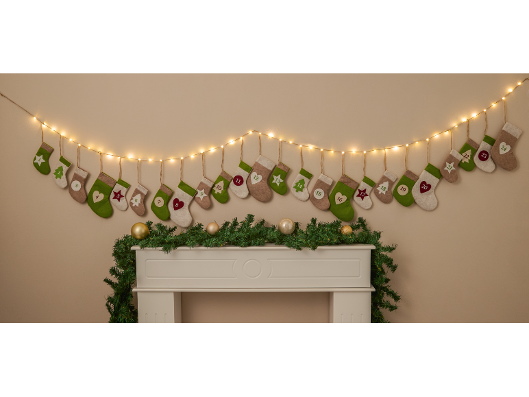 Adventskalender mit 24 kleinen Socken, die an einer Schnur über einem Kamin hängen