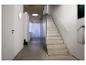 Minimalistischer Flur mit Betontreppe, Glaswand und weißen Wand- und Deckenleuchten.