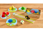Kinderspiel aus Holz mit Obstfiguren, einem Raben und einem Würfel auf einem Holztisch.