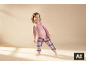 Lächelndes Mädchen in rosa Pyjama mit Croissant-Aufdruck und karierter Hose.
