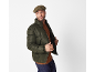 Mann mit Schiebermütze, grüner Steppjacke und braunem Pullover.