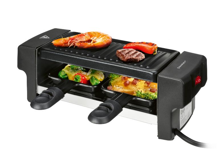 Schwarzer Raclette-Grill mit Garnelen, Steak, Paprika und geschmolzenem Käse auf Gemüse.