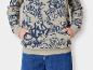 Eine beige Kapuzenjacke mit blauem Graffiti-Print und blaue Jeans.