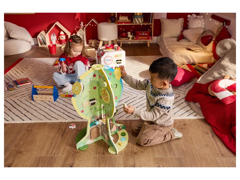 Zwei Kinder spielen mit einem Holz-Aktivitätszentrum und einem Spielzeug-Werkzeugset in einem gemütlichen Raum.