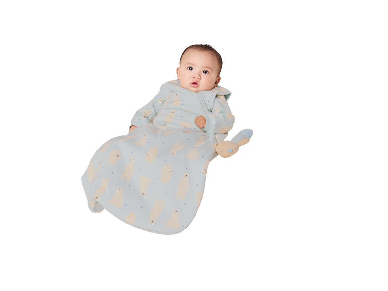 Baby in einem hellblauen Schlafsack mit Bärenmuster, das ein Plüschtier hält.