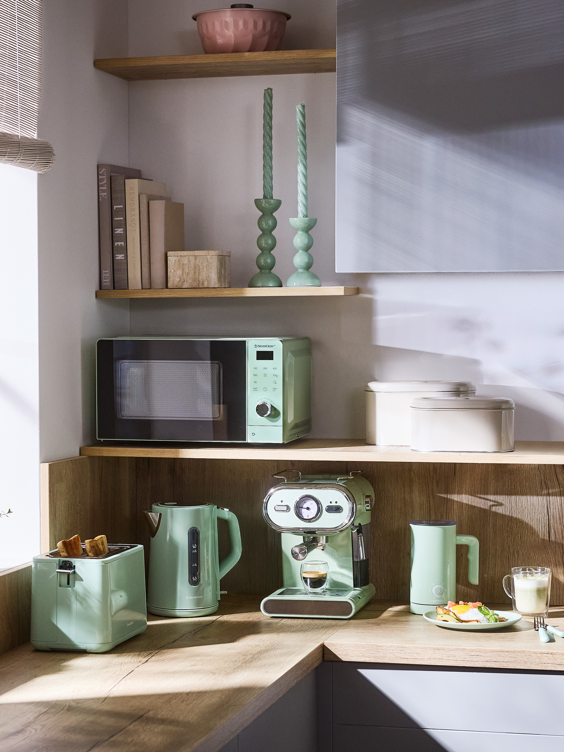 Küchenecke mit mintgrünen Geräten: Mikrowelle, Toaster, Wasserkocher und Espressomaschine.