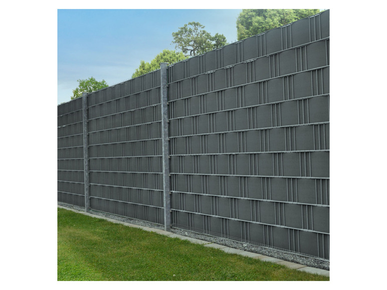 Ein grauer Metallzaun mit grünem Rasen darunter.