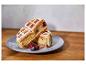 Waffeln mit Beeren und Puderzucker auf einem grauen Teller auf einem Holztisch.