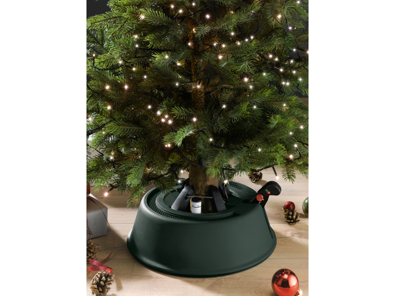 Weihnachtsbaum mit Lichtern und grünem Baumständer.