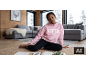 Mädchen in rosa Kapuzenpullover und schwarzen Leggings, das zu Hause auf dem Boden sitzt.