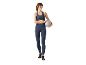 Lächelnde Frau in dunkelblauer Sportkleidung, Sport-BH und Leggings, die einen Pilatesball hält.